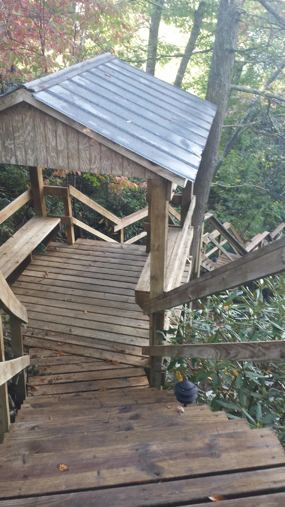Metal roofed shelter over wooden steps on a wooded walkway — Skylight Repair & Installation work by our crew in Cross River