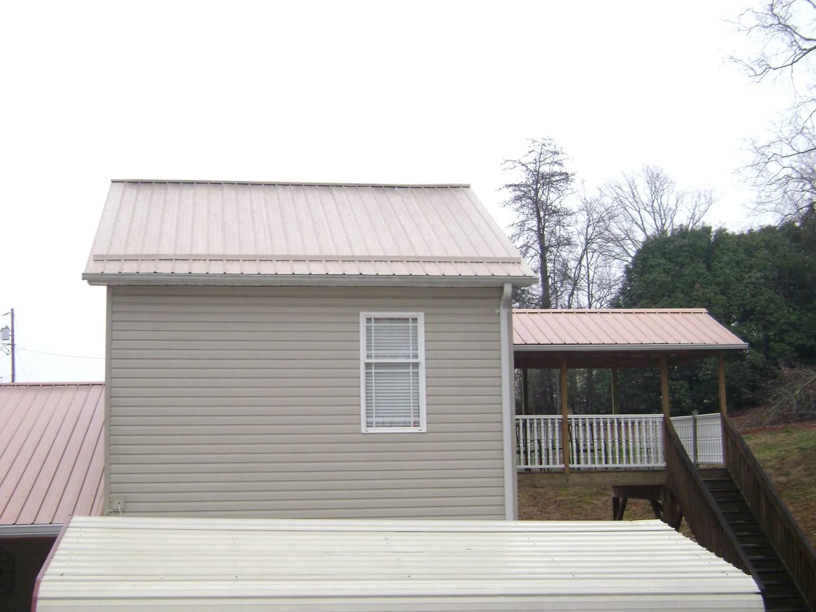 Tan metal roofs on a two story addition and attached porch, from a Roof Replacement job in Cross River