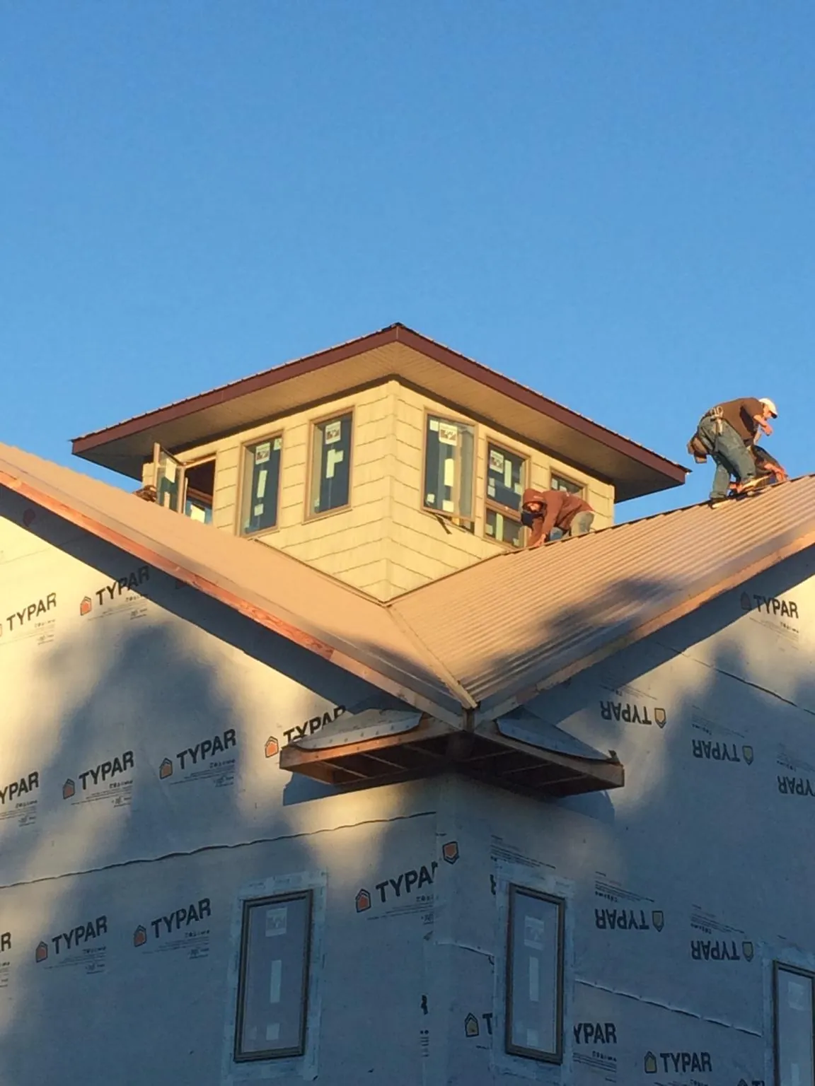 Roofers working around a rooftop cupola on a new metal roof at sunset — Roof Waterproofing in Cross River by Roofing Brothers